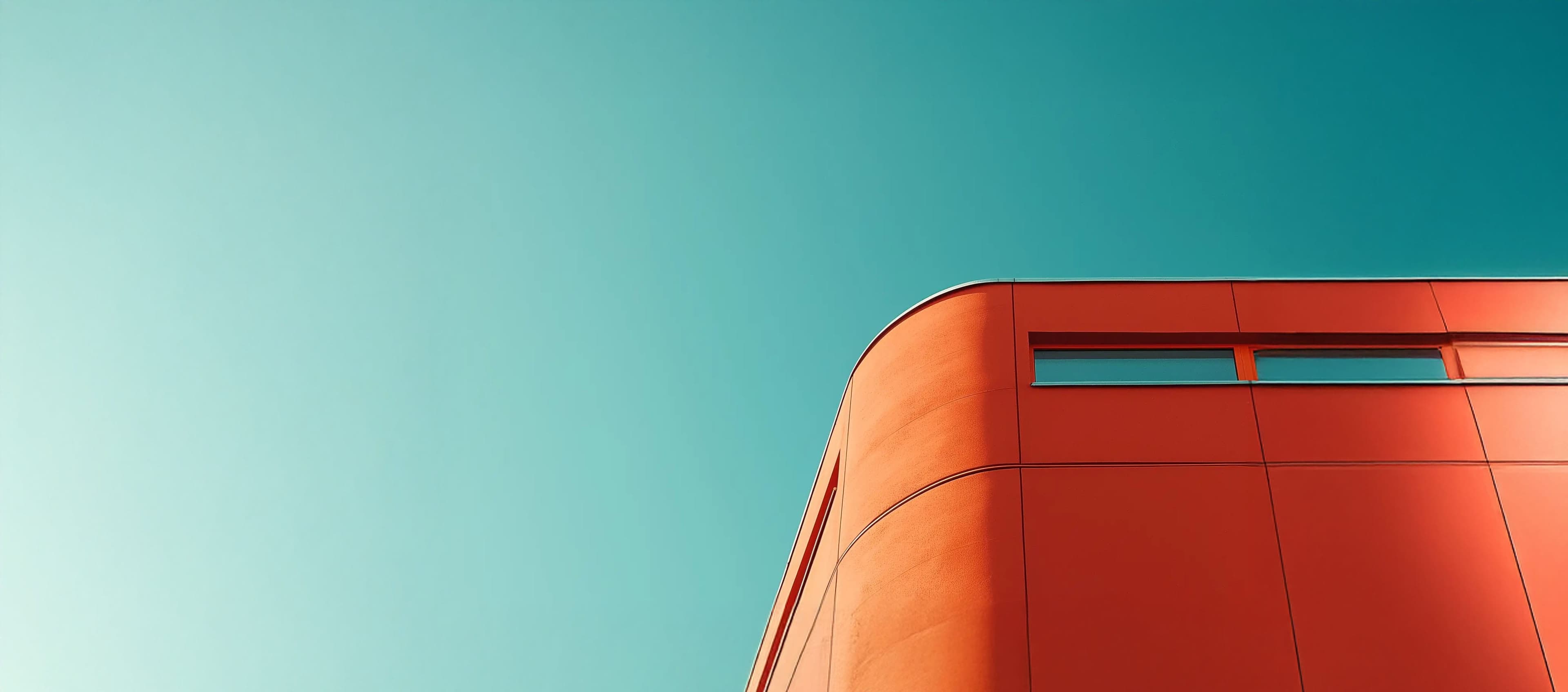 The corner of an orange building against a clear teal sky